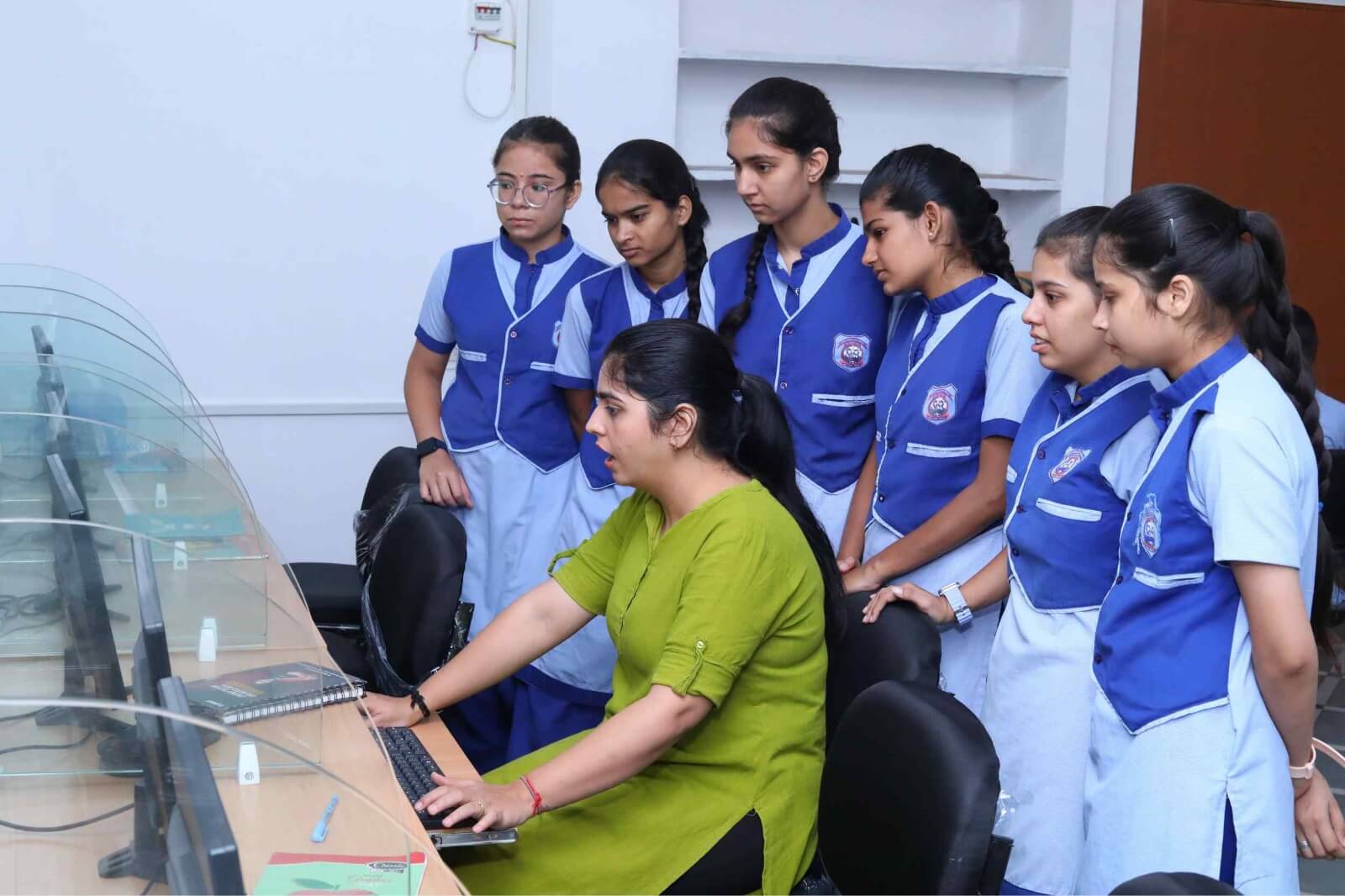 Teacher teaching a group of school girls about computers.